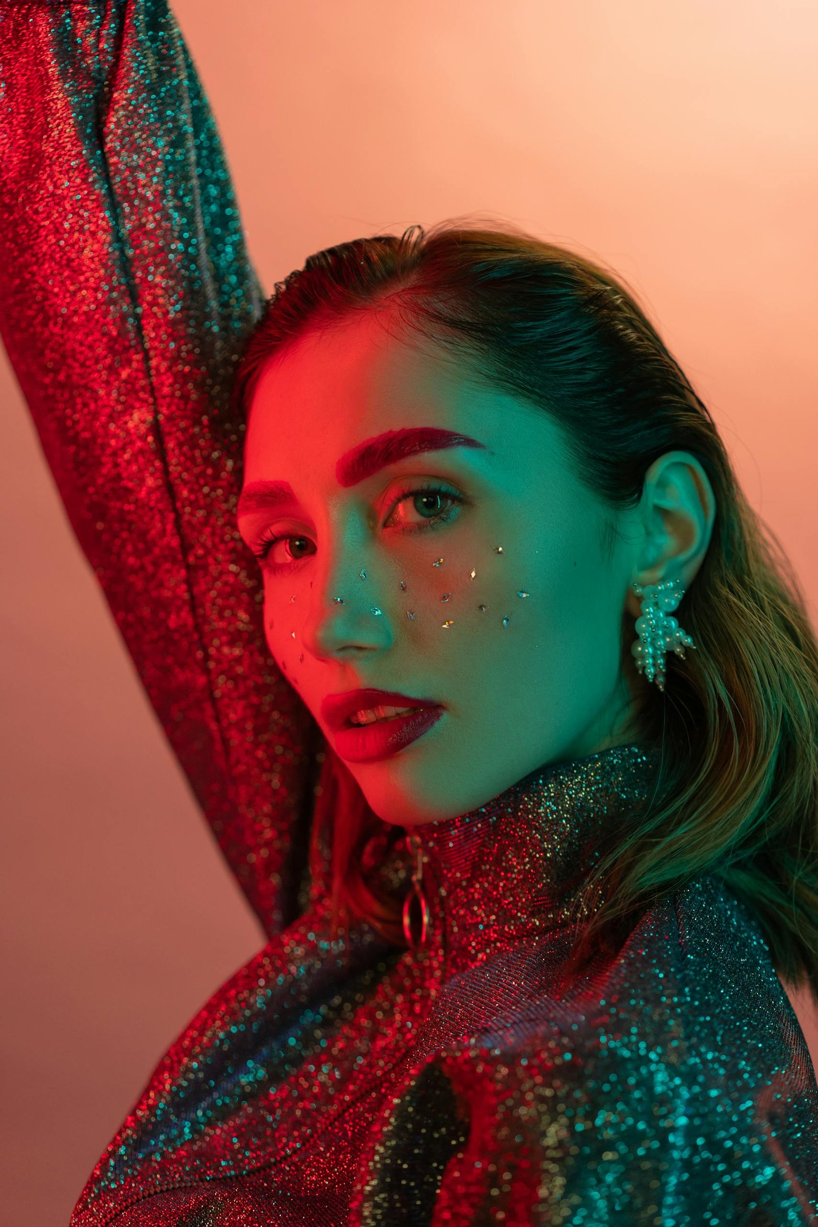 Stunning portrait of a fashionable woman with glitter makeup in vibrant lighting.