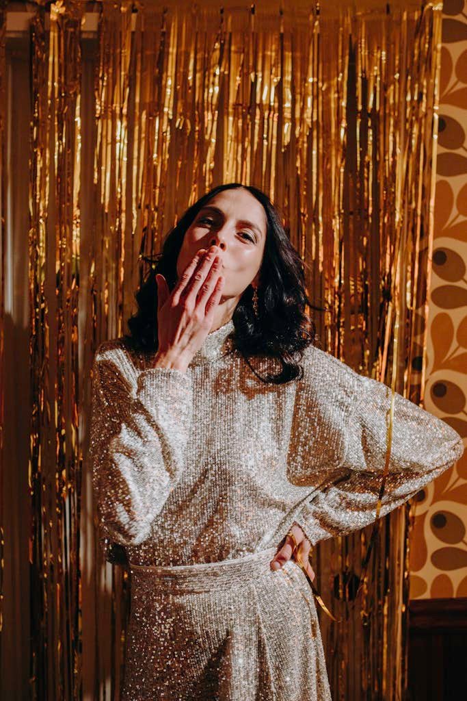 Stylish woman in elegant black dress at holiday party with gold decor