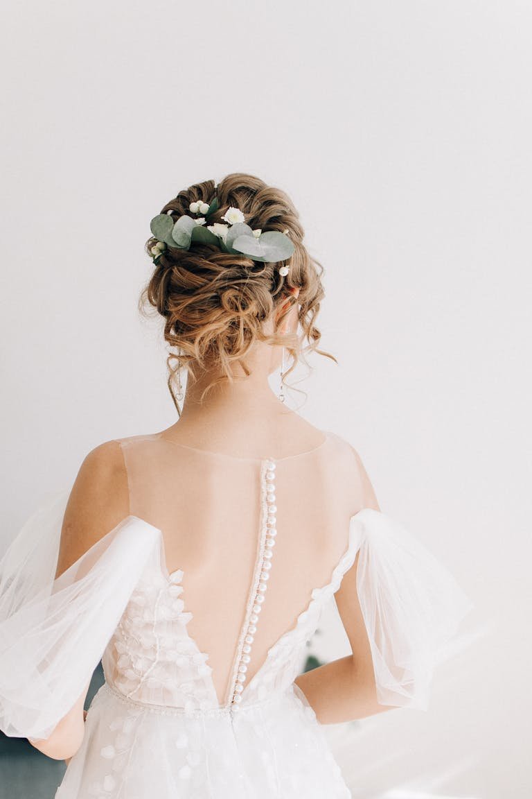 Close-up of a bride's back in a white wedding dress with floral hairstyle.