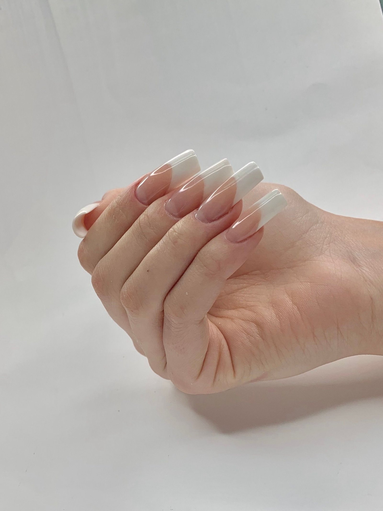 Chrome french tip nails inspiration: close-up of a hand with classic white French tip nails