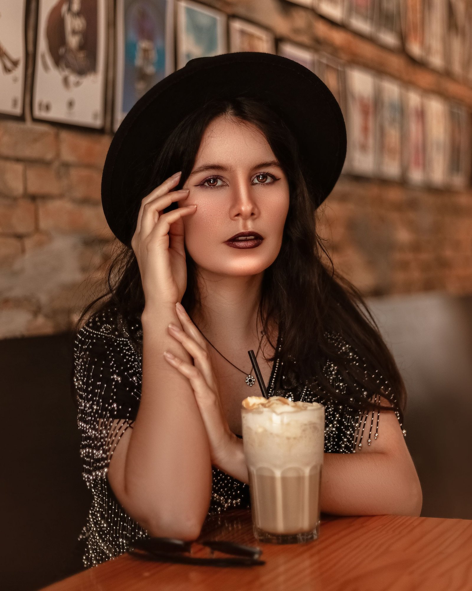 Young woman in a hat enjoying a latte in a cozy café, evoking a warm, modern vibe.